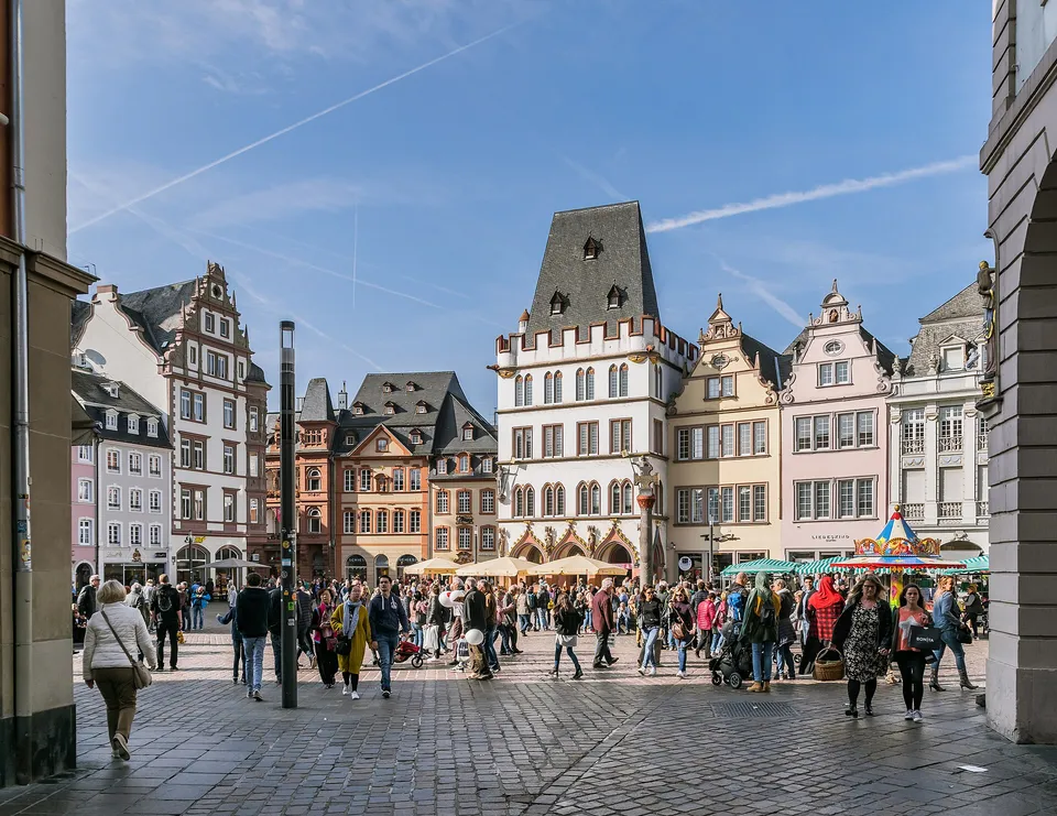 Belebter Hauptmarkt in Trier mit bunten Buergerhaeusern und Menschen