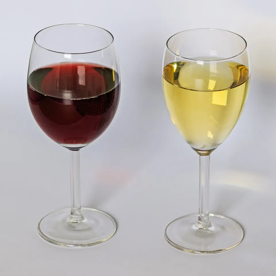 Ein Glas Weisswein und ein Glas Rotwein nebeneinander auf einem Tisch