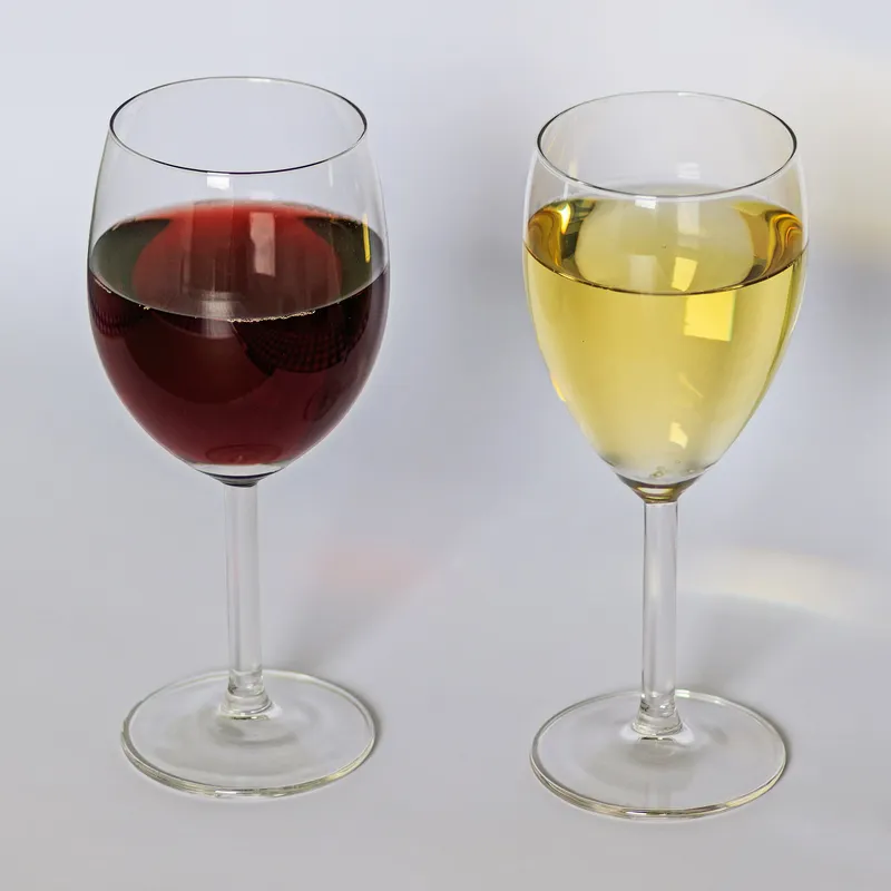 Ein Glas Weisswein und ein Glas Rotwein nebeneinander auf einem Tisch