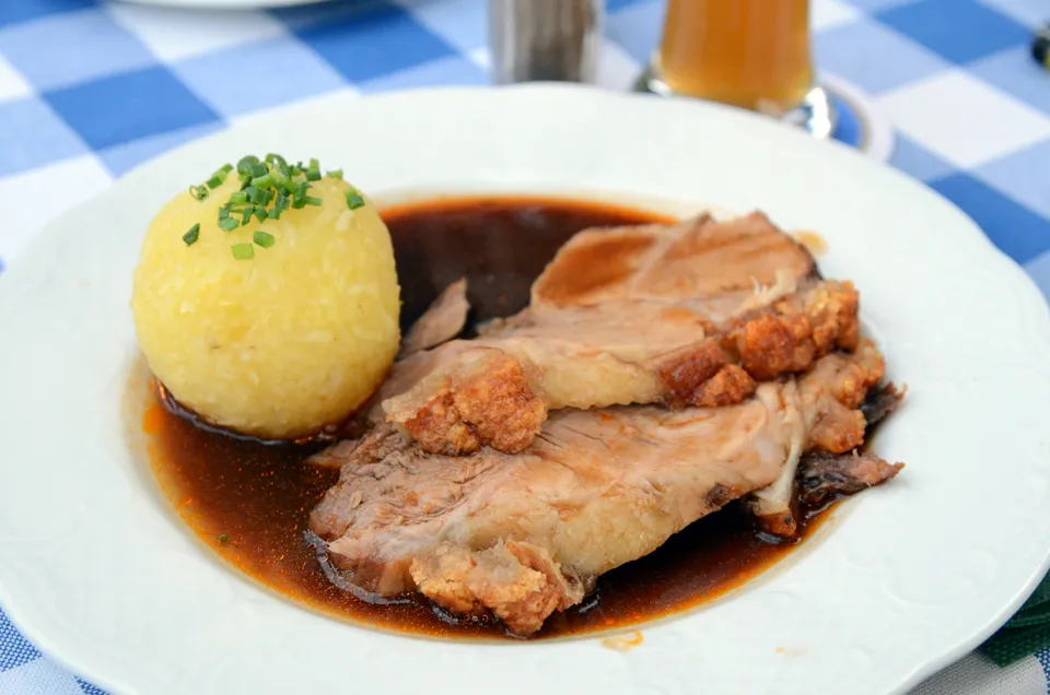 Angerichteter Schweinebraten mit Kartoffelknoedeln auf dem Teller